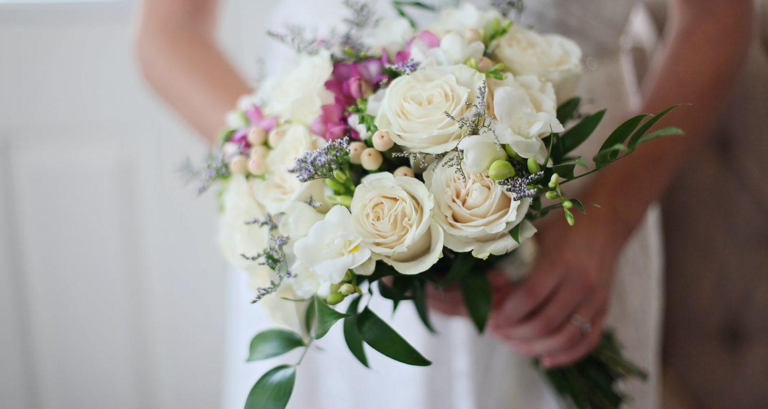 brides holding white bouquet of roses